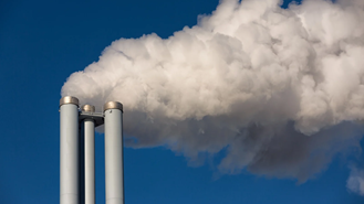Three industrial chimneys emitting clouds of white smoke